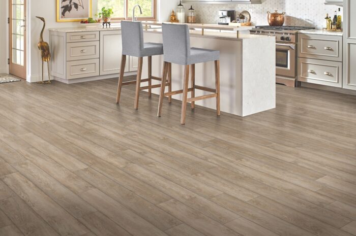 View of laminate flooring in kitchen with white island and tan chairs