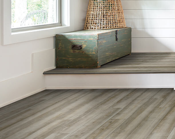 Close up of stairs with vinyl flooring and old chest on top.