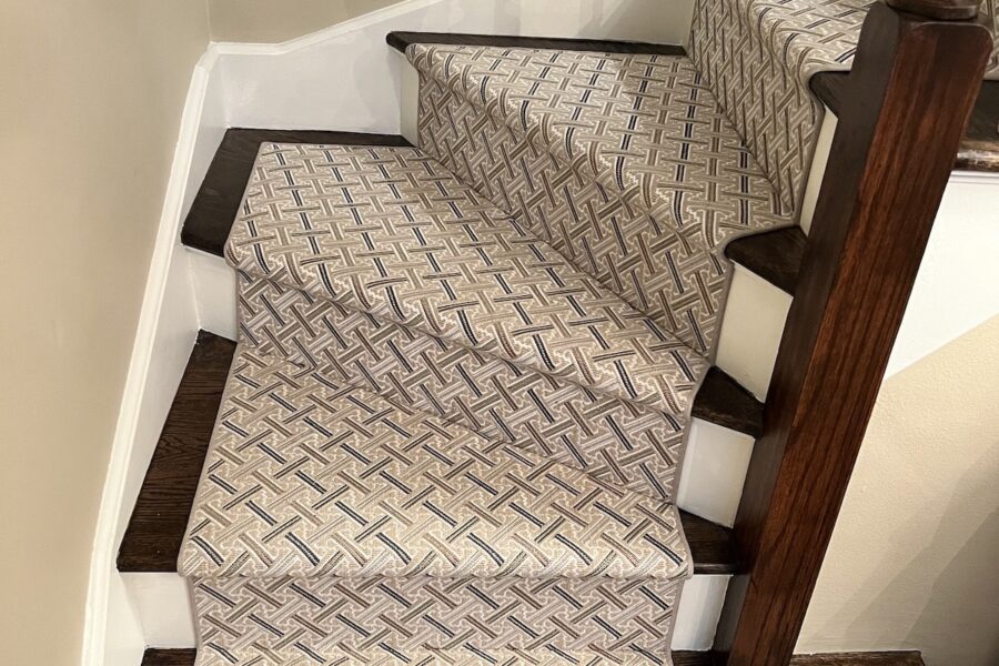 view of tan patterned floor runner carpet over dark wood stairs.