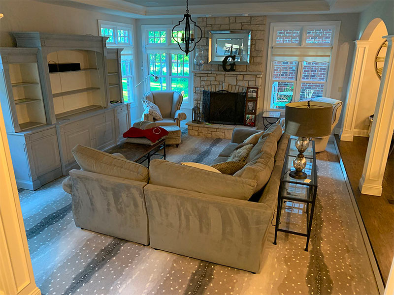 Beautiful living room with patterned carpet, gray sectional couch and gray wood entertainment center.